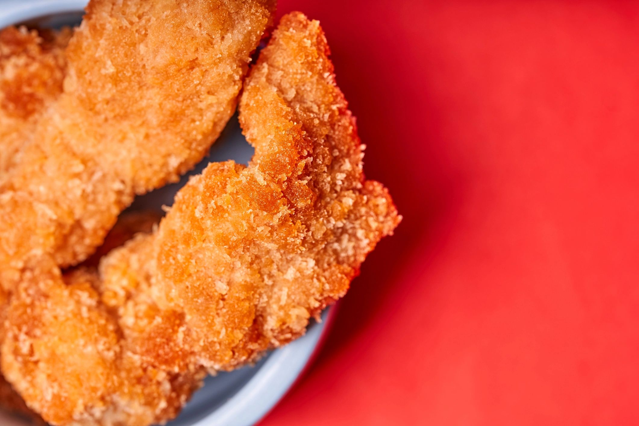fried chicken tenders on red background